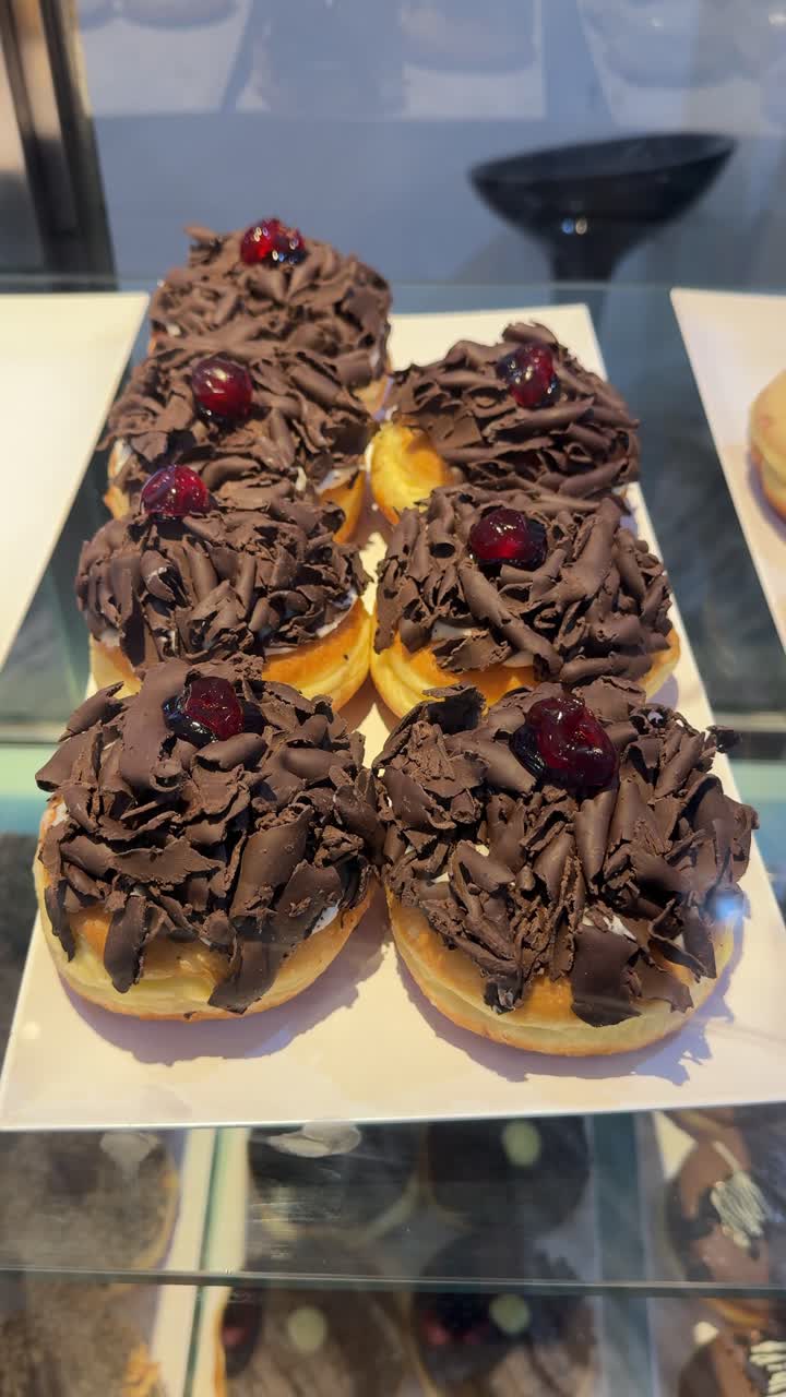 Ciambelle al cioccolato e ciliegia esposte in una vetrina di pasticceria