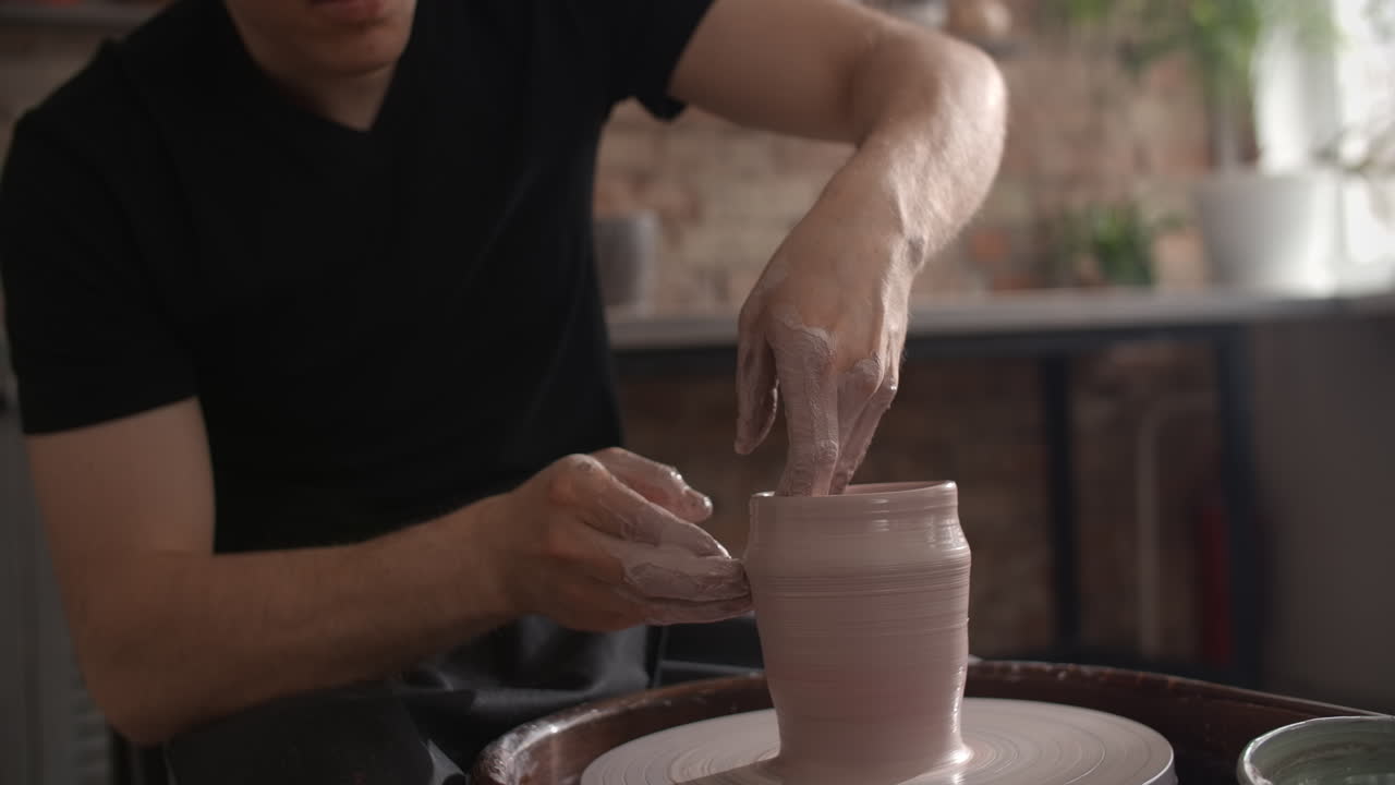 Person Shaping a Clay Pot on a Pottery Wheel