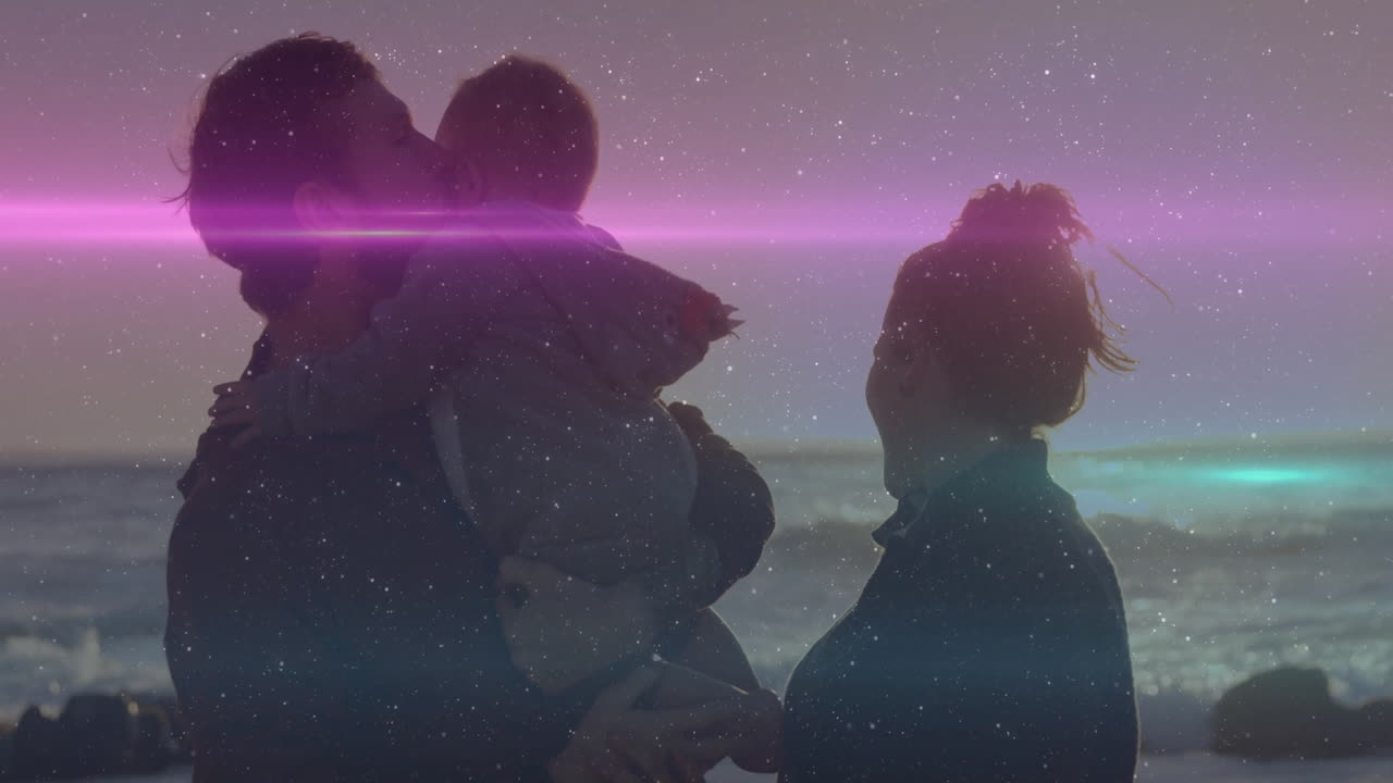 man holding baby facing woman at beach, displaying health chart with star speckles and light flare