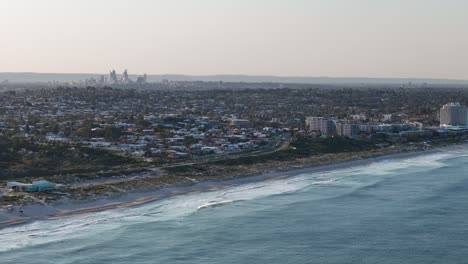 slow mo aerial view of perth city skyline with scarborough beach in the foreground