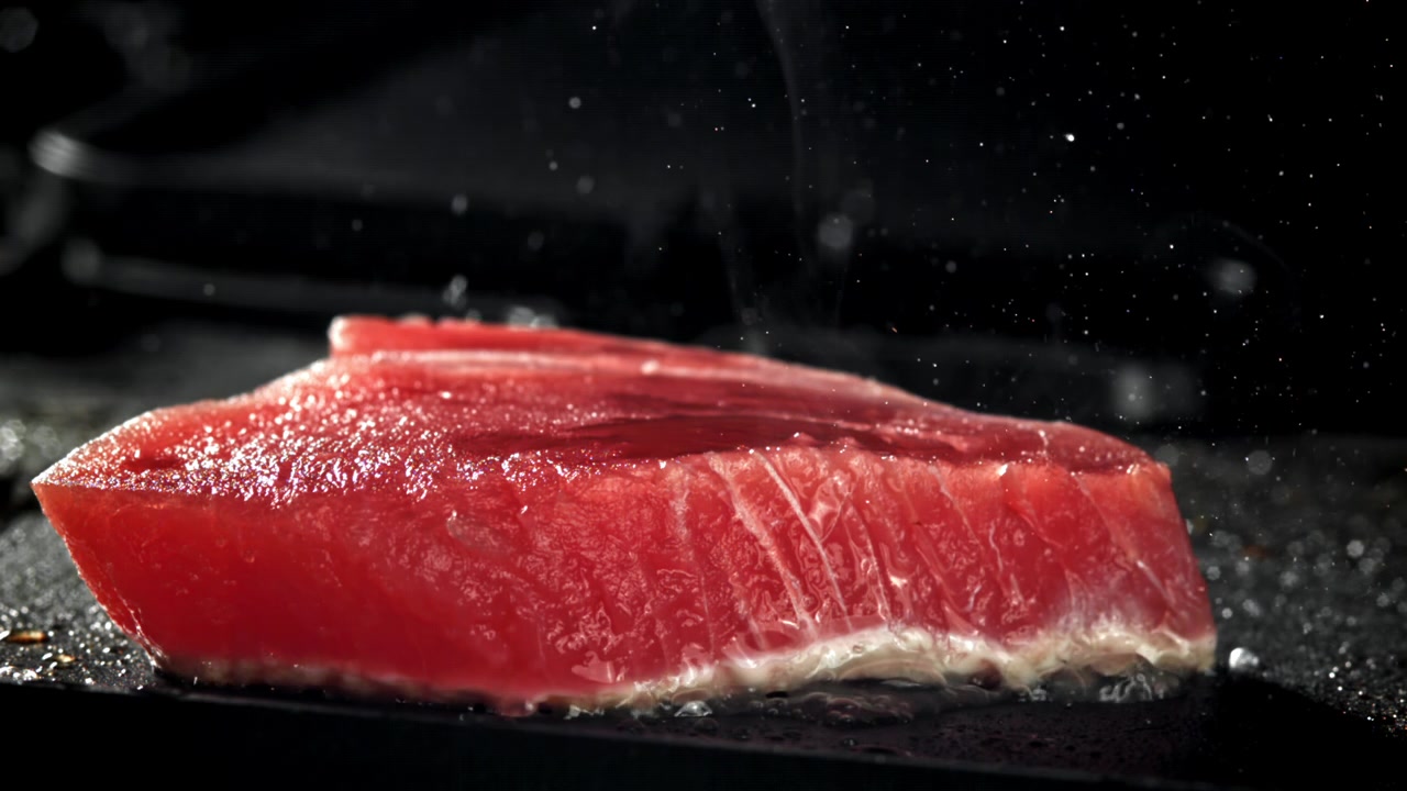 Filetto fresco di tonno rosso che si scotta su una padella rovente