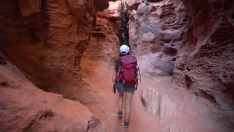 female hiker with backpack walking into narrow canyon, hiking trail in st