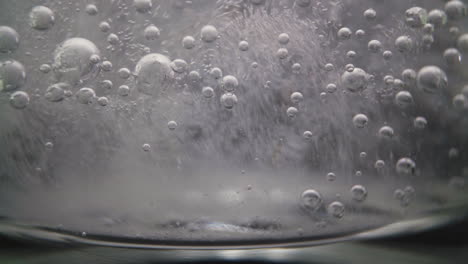 glass with clear sparkling vitamin water on dark background