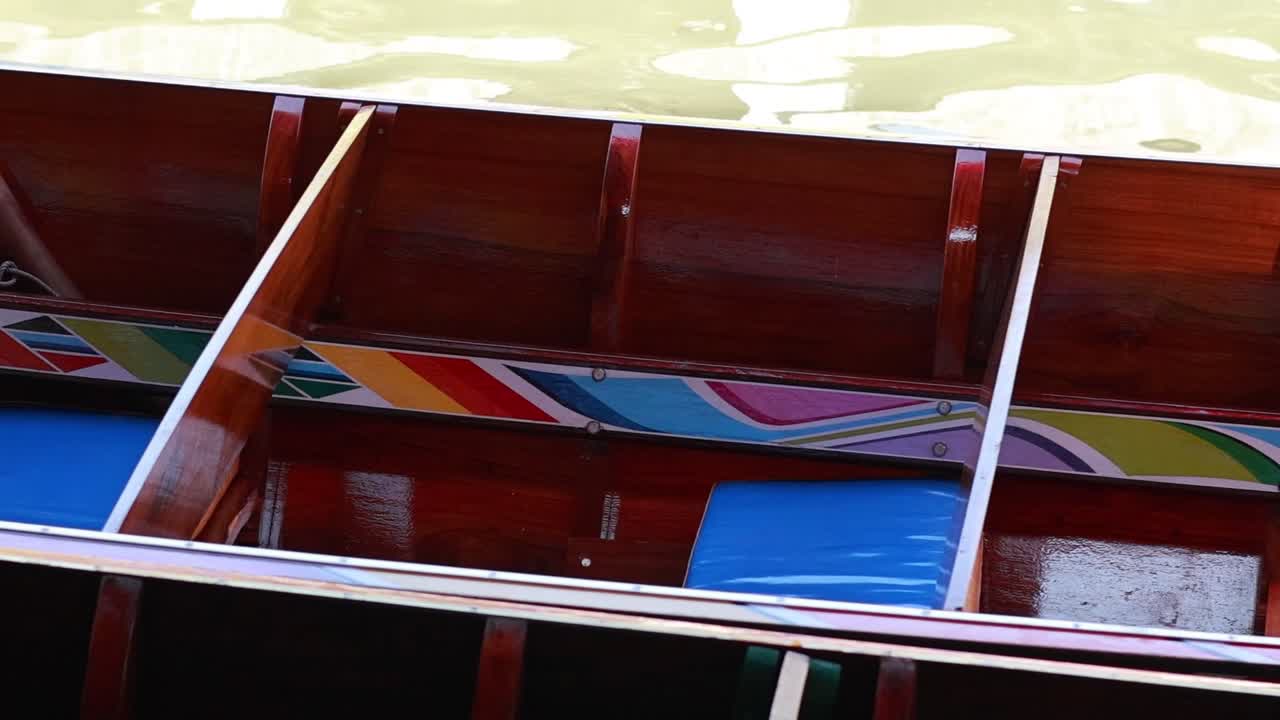 Close-up view of vibrant wooden boat interiors with colorful patterns floating on serene water.