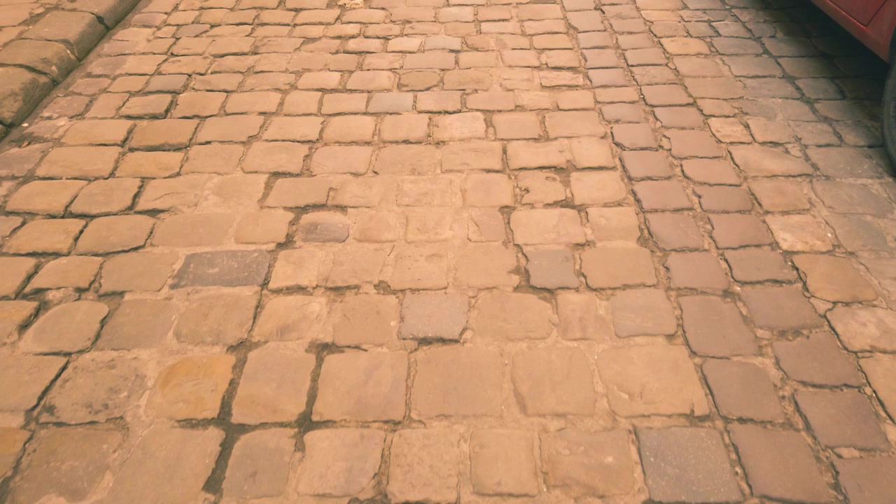 Old street of paving stone and parked cars.
