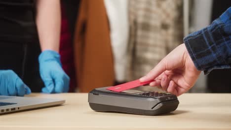 paying with credit bank card in shop. buying clothes in store. contactless shopping in supermarket during coronavirus pandemic.