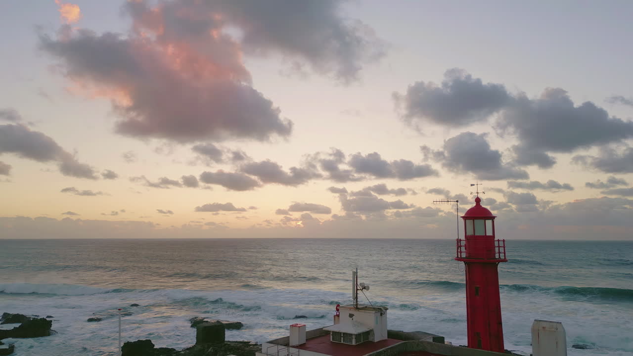 Aerial evening lighthouse standing on rough coast washed by powerful ocean water