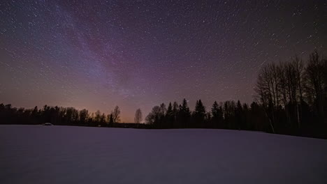 dreamy night sky time lapse with orbiting stars over snowy woodland