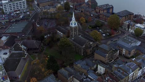 Aerial-view-of-Gravesend-town,-Kent,-UK-with-a-pan-up-reveal-of-Tilbury-docks-and-the-river-Thames