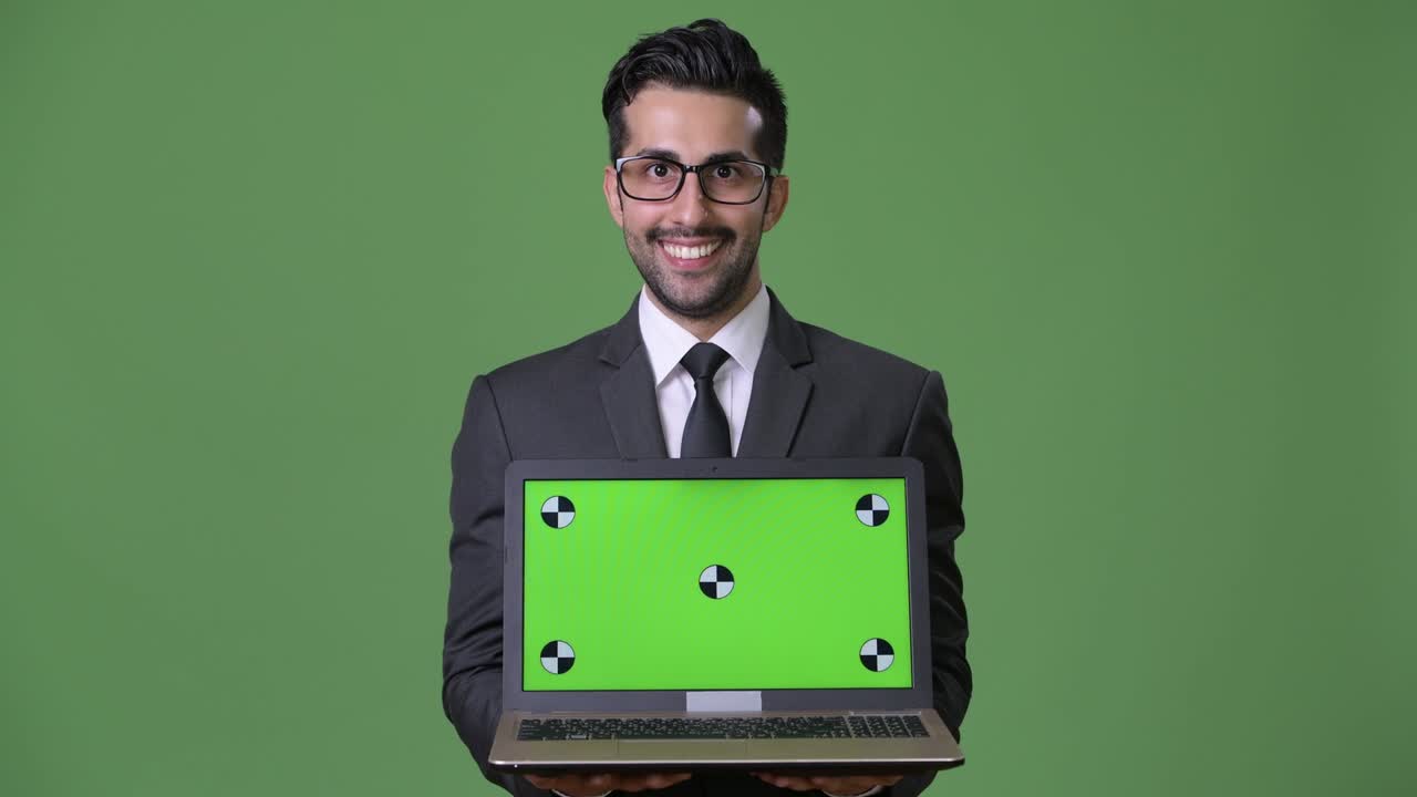 joven empresario persa barbudo y guapo contra un fondo verde