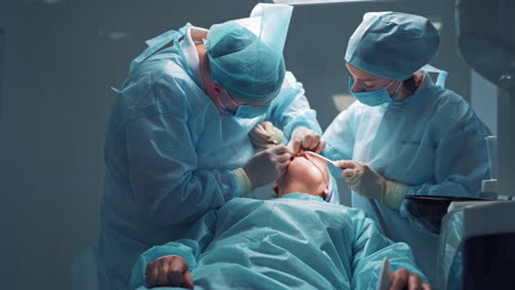 dentist in medical clothes is treating a patient in a dental office. orthodontist works with an assistant. the client is treating his teeth.