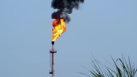 a large flaming gas tower with billowing black smoke