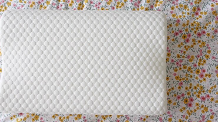 Cuscino in memory foam bianco su biancheria da letto floreale