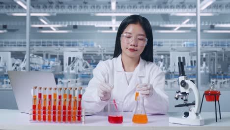 asian woman scientist making experiment with test tube and typing on a laptop in laboratory with microscope. carrying out experiments, working in the lab analyzing finding sample test tube