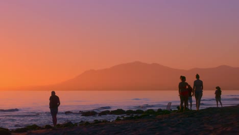 silueta de varias personas en la playa durante la puesta de sol