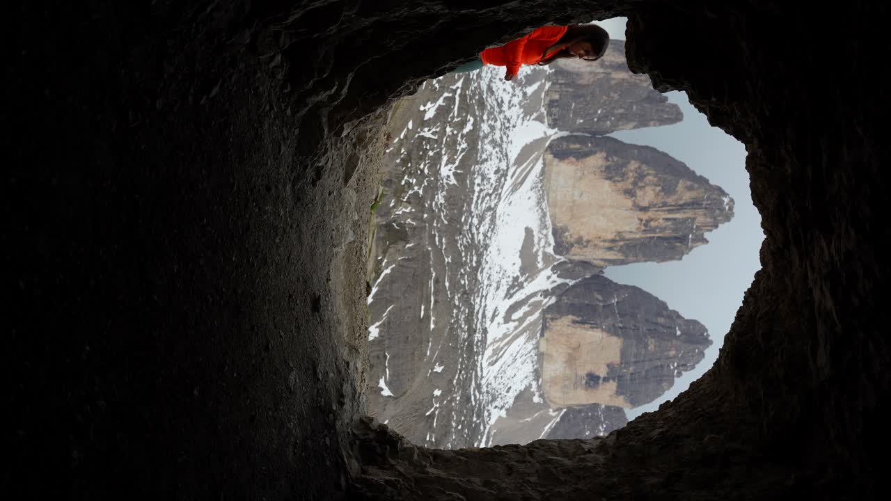 트레 시메 디 라바레도 (tre cime di lavaredo) 의 수직 비디오는 동굴을 통해 볼 수 있으며, 하이커 여성이 나타납니다.