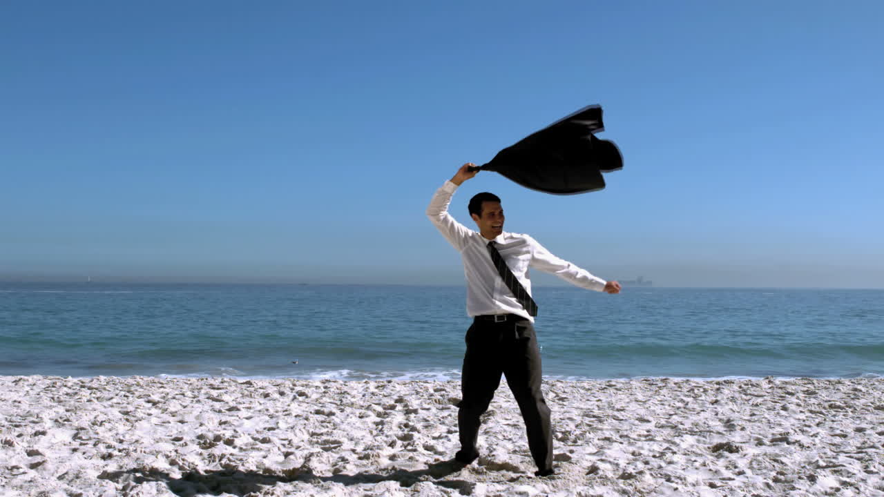 사업가 가 옷 을 벗고 자켓 을 해변 에 던지고 있다