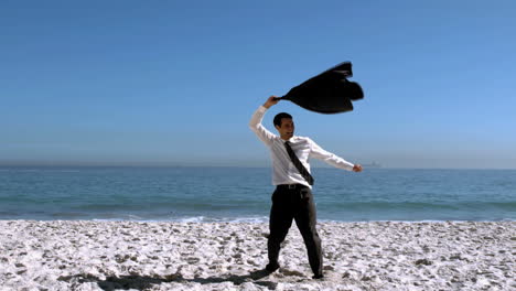 businessman undressing and throwing his jacket on the beach