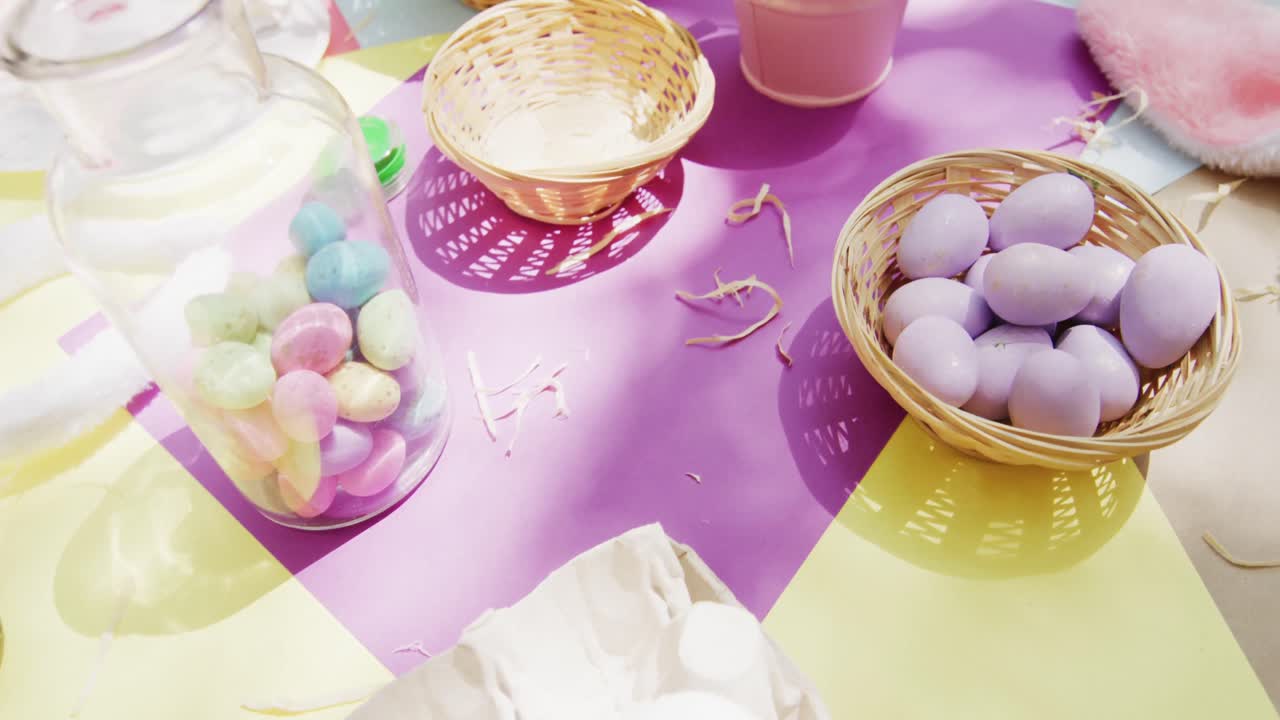 Sunny table in garden with baskets, painted and sugar eggs for easter celebration, slow motion