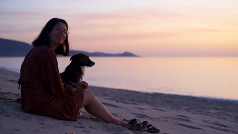 mujer acariciando al perro en la playa