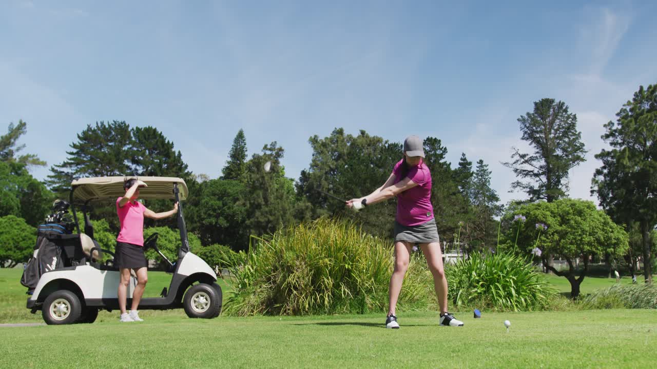 두 명의 백인 여성이 골프를 치고 한 명은  ⁇ 커에서 총을  ⁇ 고 있습니다.