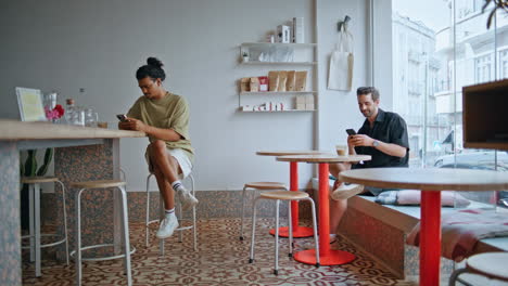 two men sitting coffeehouse interior with smartphones. visitors relaxing in cafe