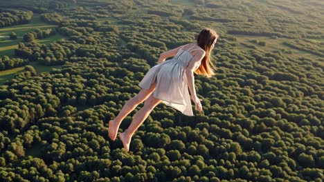 girl flying over a forest at sunset