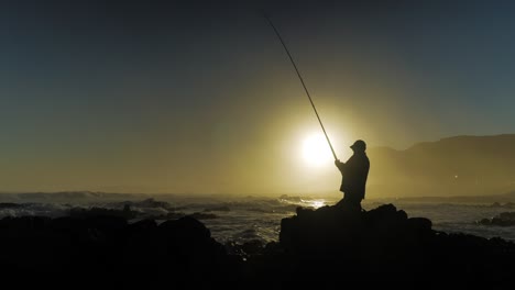 Pescador-En-Las-Rocas-Parece-Estar-Pescando-Un-Pez,-Pero-Es-Algo-Totalmente-Diferente