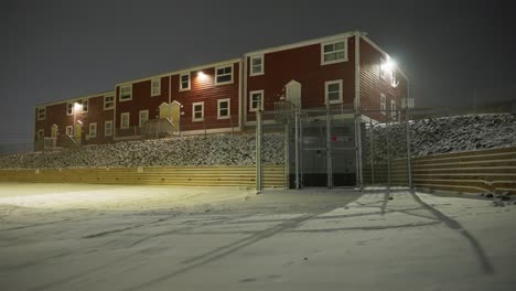 red building outside at night with snow blowing