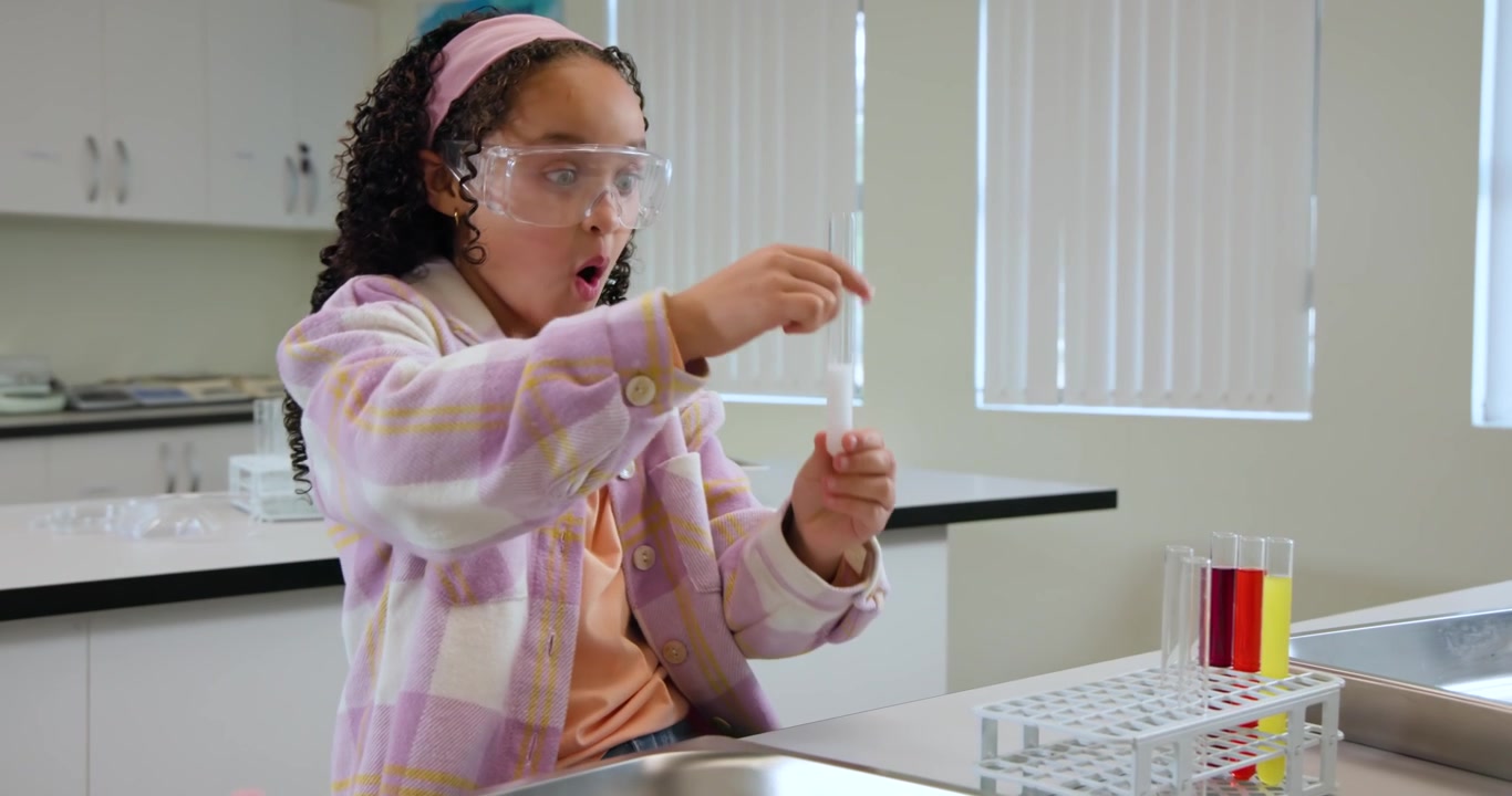 African American teen student pipetting from tray at lab, inspecting test tube and wearing goggles