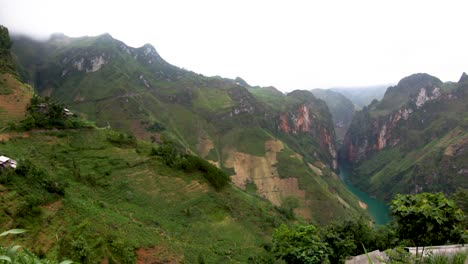 Slow-pan-left-of-giant-picturesque-valley-with-a-turquoise-blue-green-riving-cutting-through-below