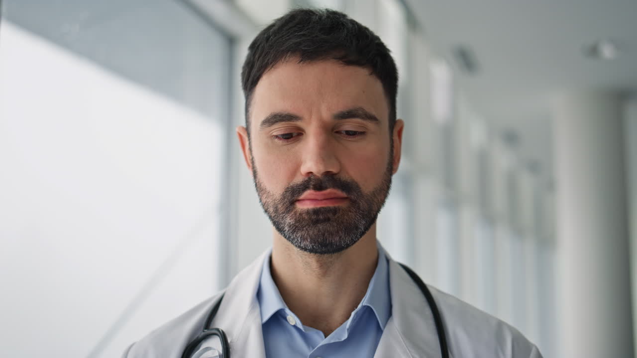 Primer plano de médico barbudo posando en sala de hospital. Profesional sonriente de pie
