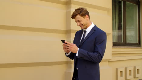 cheerful businessman using mobile phone outdoors. happy professional