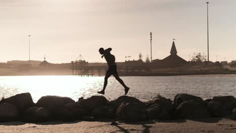 Hombre-Corriendo-Sobre-Las-Rocas-En-La-Playa