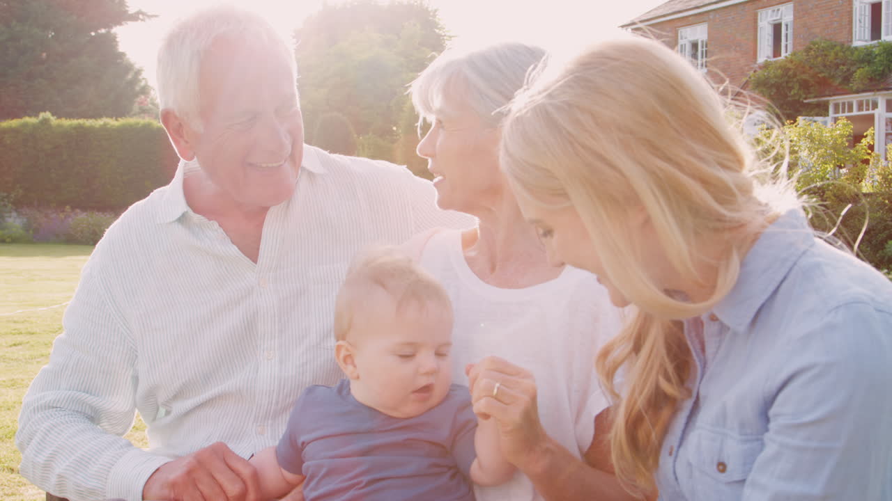 할아버지 와 할머니 는 아기 손자 와 성인 딸 과 함께 야외 에 앉아 있다