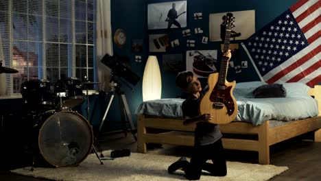 expressive youngster playing guitar in bedroom