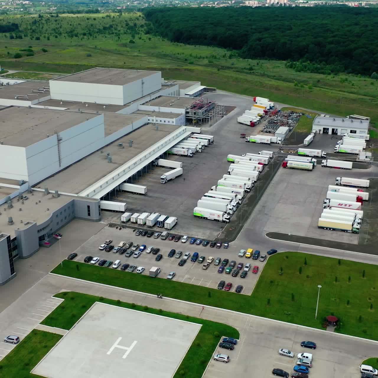 Industrial zone with parking places. Cars and trucks near the modern manufacturing situated on field. Camera rising up