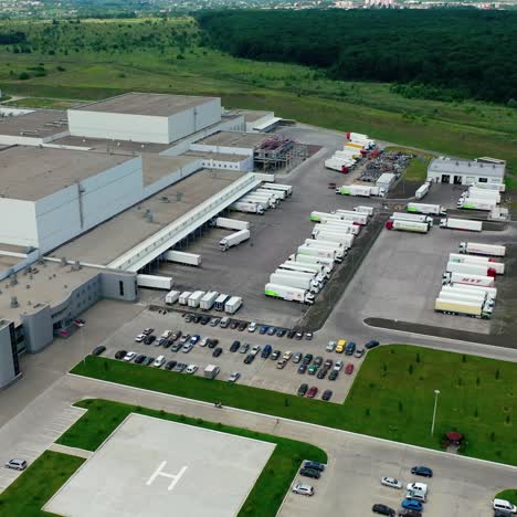 industrial zone with parking places. cars and trucks near the modern manufacturing situated on field. camera rising up