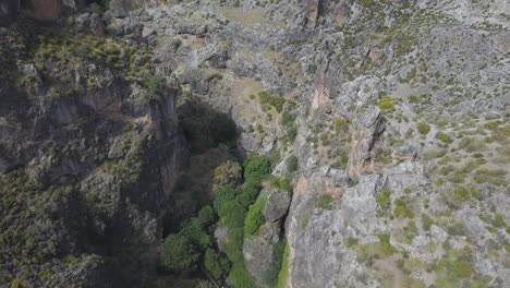 Toma-Aérea-Inclinada-Hacia-Abajo-Sobre-Montañas-Rocosas-Con-Un-Río-En-Lo-Profundo-Del-Acantilado-En-El-Sistema-Ibérico