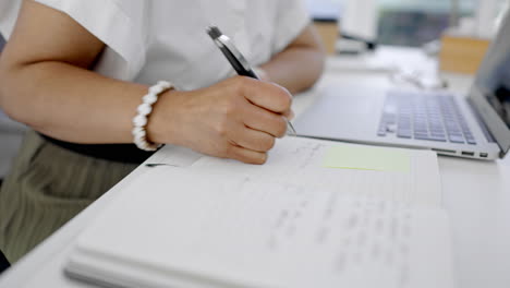 hands, woman and writing in notebook with laptop