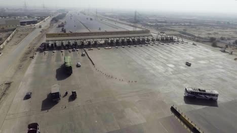 Vista-Aérea-De-Una-Plaza-De-Peaje-De-La-Autopista-De-La-Ciudad,-Vehículos-Pesados-Y-Otros-Que-Ingresan-Y-Cruzan