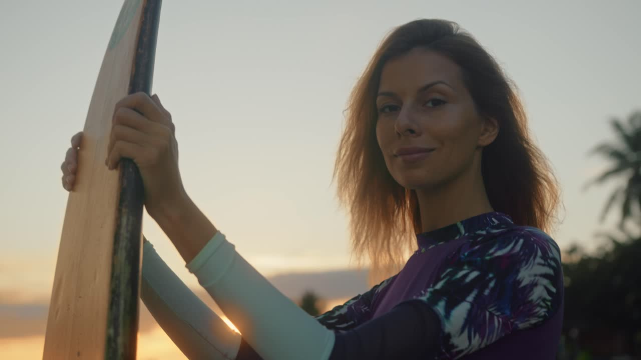 mujer con tabla de surf al atardecer