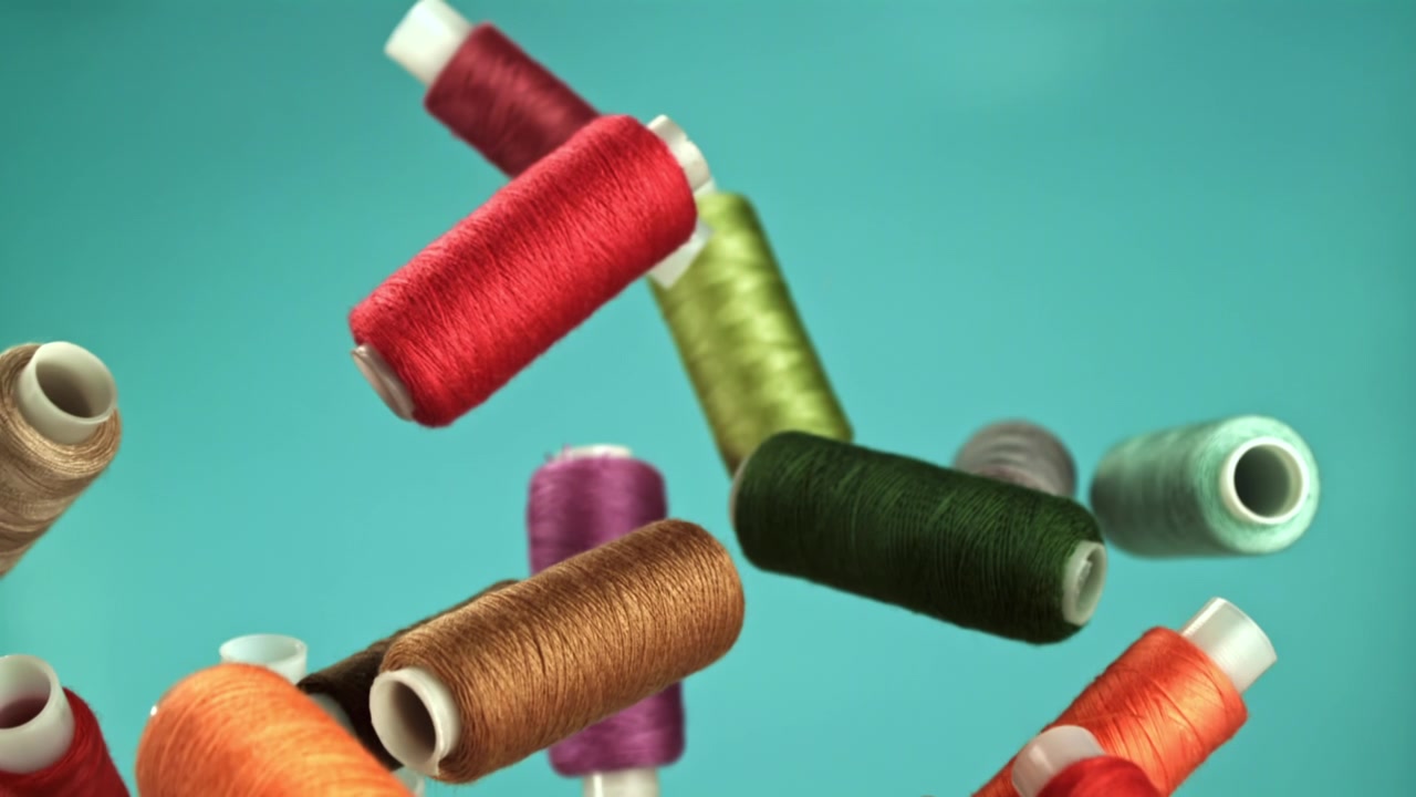 Colorful Sewing Thread Spools Falling in Slow Motion