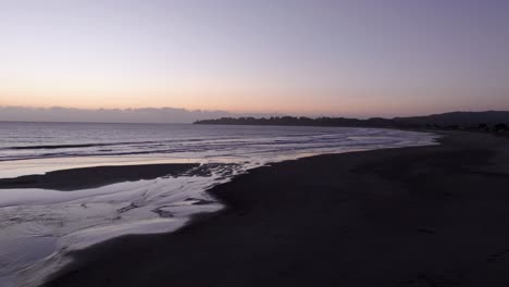 Drone-shot-flyover-of-a-beach-at-dusk-in-California-at-golden-hour