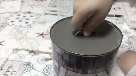 young boy child toddler inserting a coin into a tin foil money saving piggy bank financial investment future savings