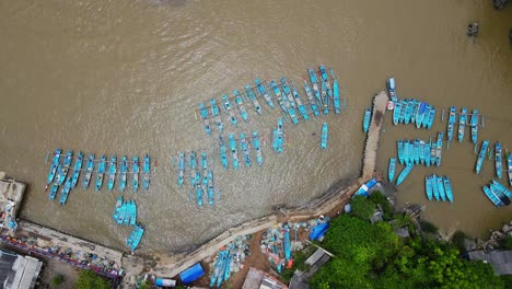 overhead drone shot of fishing boats lined up in the harbour - baron beach, yogyakarta, indonesia