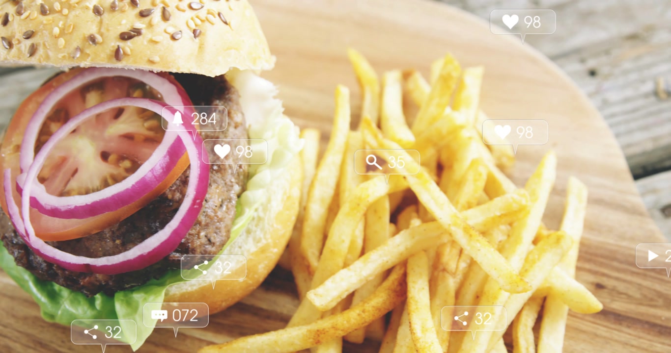 Vertical video: Showing social icons causing burger slide onto board on patio with fries for likes