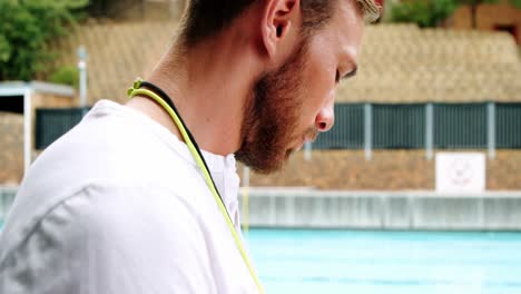 entrenador de natación escribiendo en el clipboard cerca de la piscina
