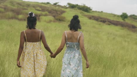 dos chicas caminan a lo lejos mientras se toman de la mano