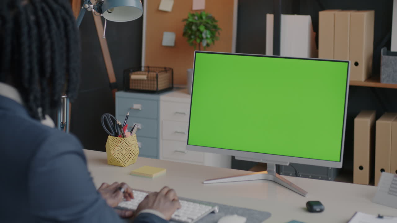 Man Working at a Computer with a Green Screen Monitor in Modern Office